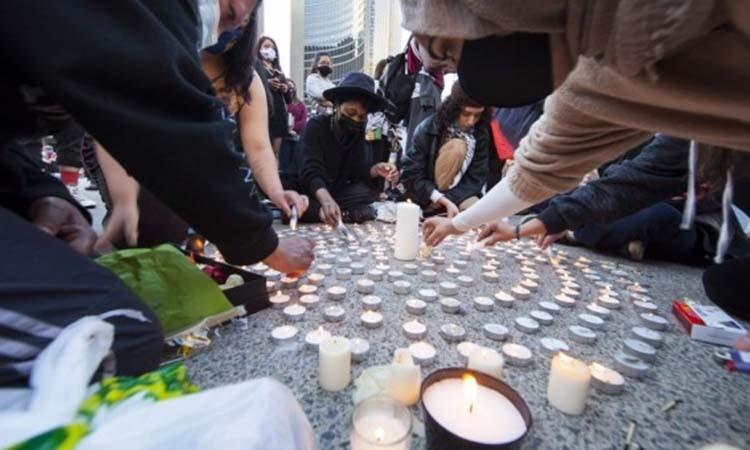 People light candles as they take part in a memorial event for the 215 children