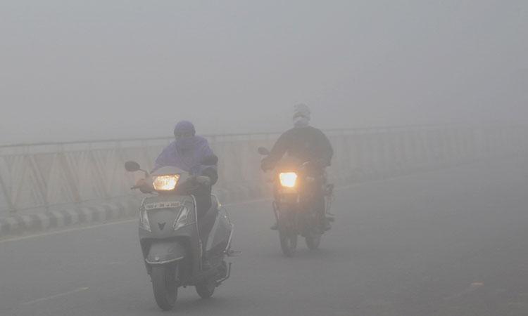 Commuters-make-their-way-amid-low-visibility-due-to-dense-fog-on-a-cold-day