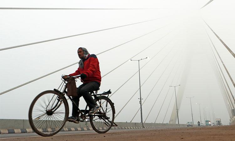 A-man-paddles-the-cycle-as-he-passes-through-Signature-bridge-on-a-cold-and-foggy-morning-in-New-Delhi