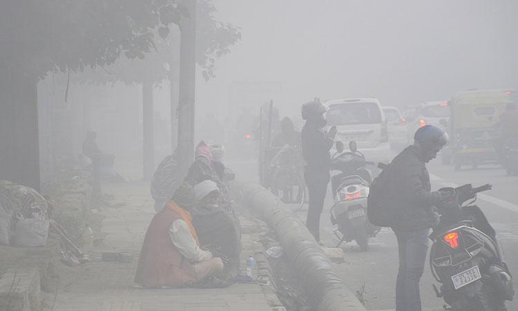 Commuters-and-homeless-people-seen-on-a-road-amid-dense-fog-on-a-cold-day-in-New-Delhi