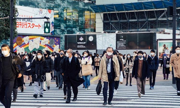 People-wearing-face-masks-walk-through-the-Shibuya-scramble-crossing-in-Tokyo,-Japan